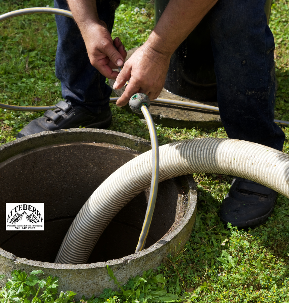 A person holds a hose while working on a septic tank outdoors, standing on grass. A large hose is placed into the open tank. The logo Atteberry is visible on the lower left side. Septic repair.