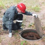 A licensed septic repair contractor inspecting a residential septic tank outdoors